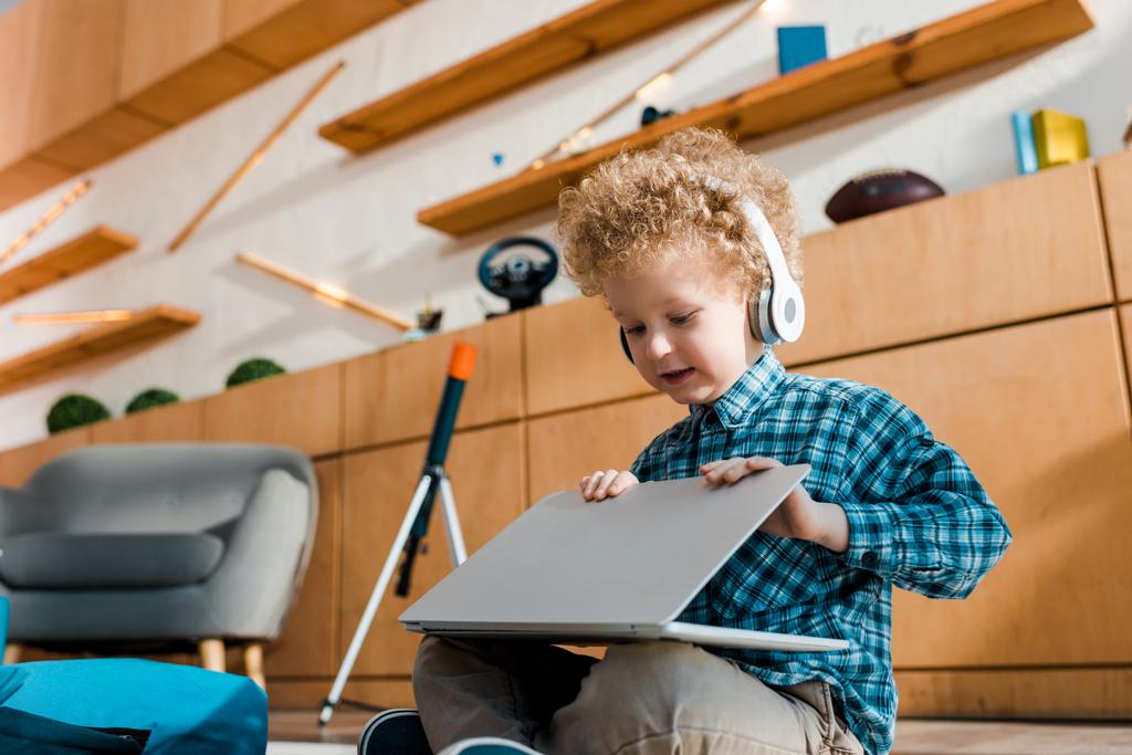 Kablosuz kulaklıkla müzik dinlerken dizüstü bilgisayar kullanan sevimli çocuk.  - Fotoğraf, Görsel