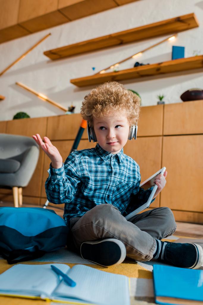 вибірковий фокус спантеличеної дитини в навушниках, що тримає цифровий планшет і показує жест згинання
  - Фото, зображення