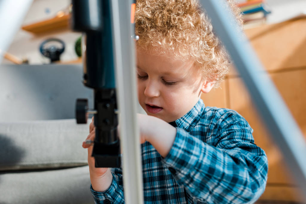 selective focus of curly kid looking at telescope  - Photo, Image