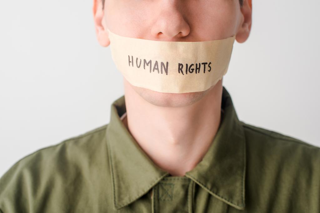 vista recortada del hombre con cinta adhesiva en la boca con letras de derechos humanos aisladas en blanco
 - Foto, imagen