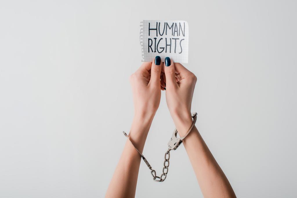 Ellerinde kelepçe, ellerinde insan hakları yazılı kağıtlar olan beyaz bir kadın görüntüsü.  - Fotoğraf, Görsel