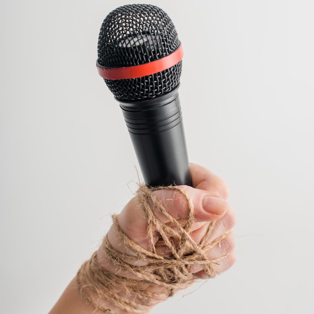 abgeschnittene Ansicht einer Frau mit gefesselter Hand, Mikrofon isoliert auf weiß, Konzept der Meinungsfreiheit  - Foto, Bild