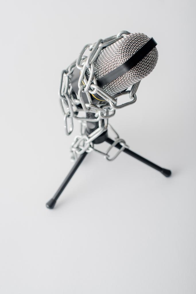 foyer sélectif du microphone dans les chaînes métalliques isolé sur blanc, concept de liberté d'expression
  - Photo, image