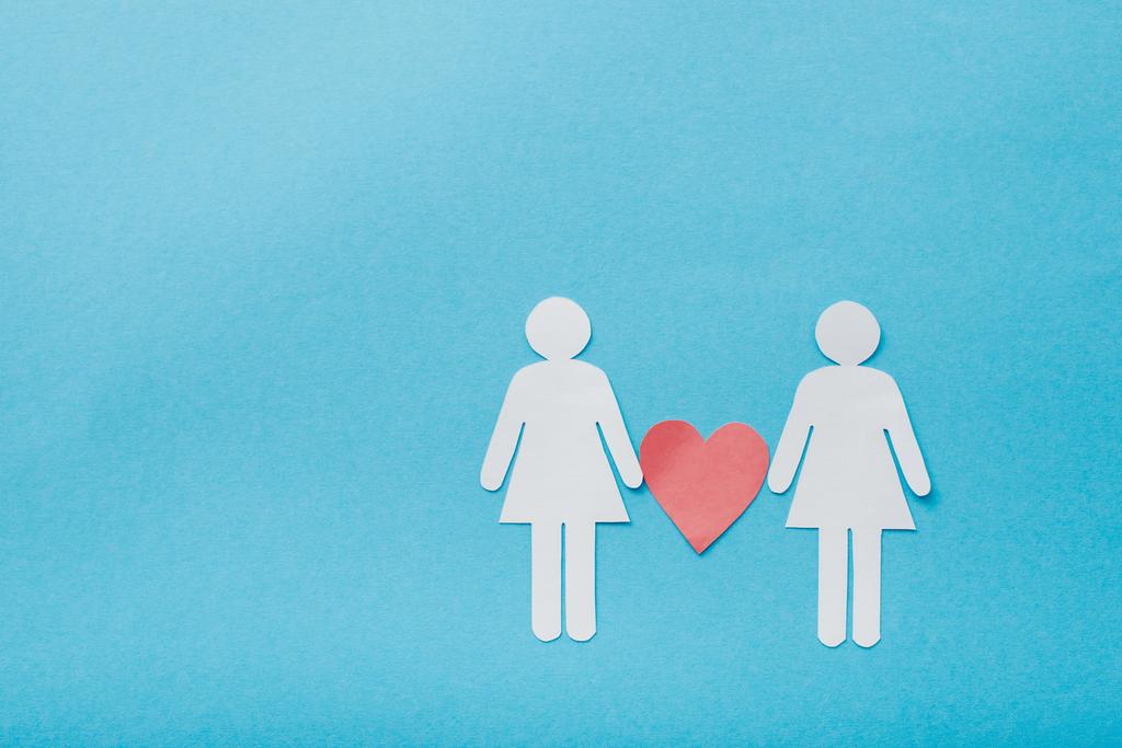 κορυφαία άποψη των κομμένων από χαρτί μορφών του ομοφυλόφιλου ζευγαριού με την καρδιά απομονωμένη στο μπλε, έννοια της ισότητας των φύλων  - Φωτογραφία, εικόνα