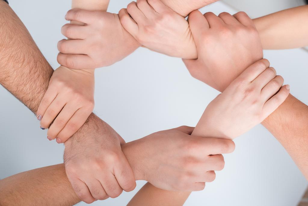 κορυφή άποψη των γυναικών και των ανδρών με ενωμένα χέρια μαζί σε λευκό, έννοια των ανθρωπίνων δικαιωμάτων  - Φωτογραφία, εικόνα
