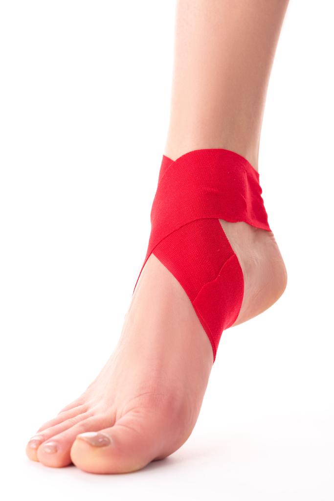 Cropped view of kinesiology tapes on foot of woman on white background - Photo, Image