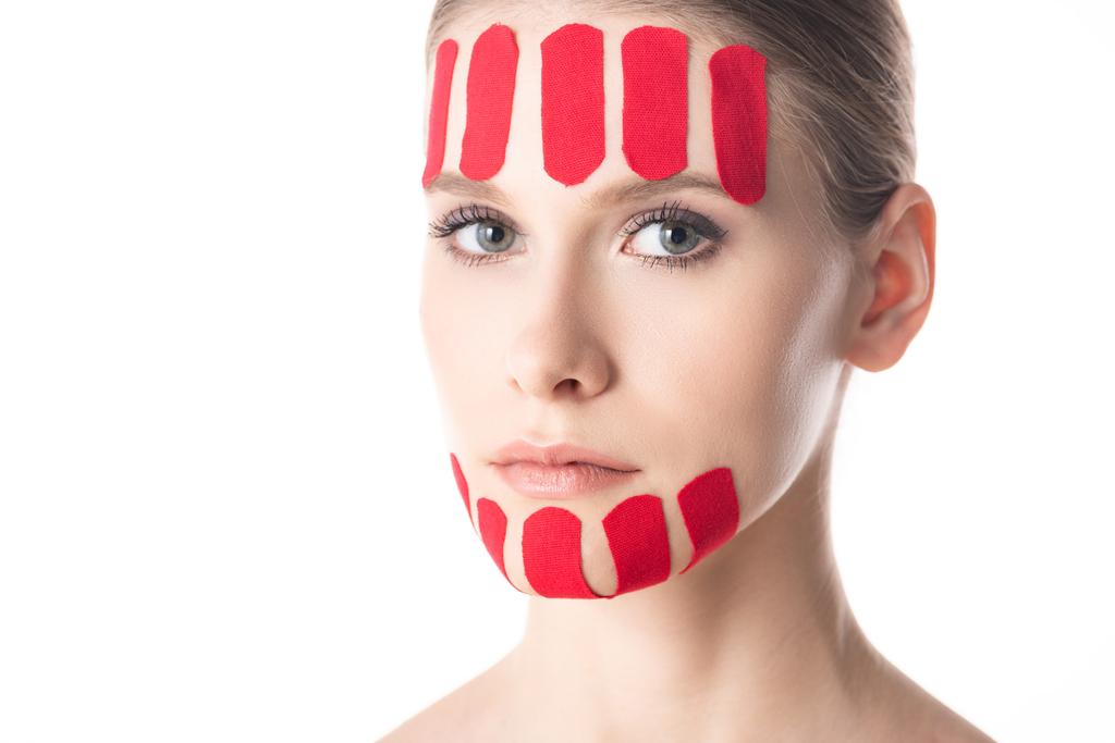 Beautiful girl with kinesiology tapes on chin and forehead looking at camera isolated on white - Photo, Image