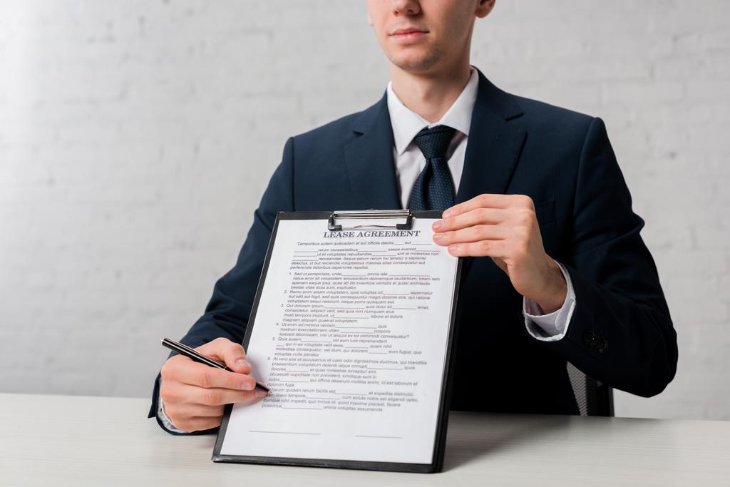 cropped view of realtor holding clipboard with lease agreement lettering on white - 写真・画像