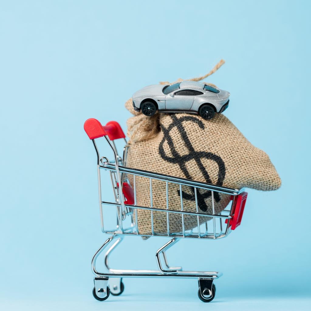 small shopping cart with dollar bag and toy car on blue, leasing concept - Photo, Image