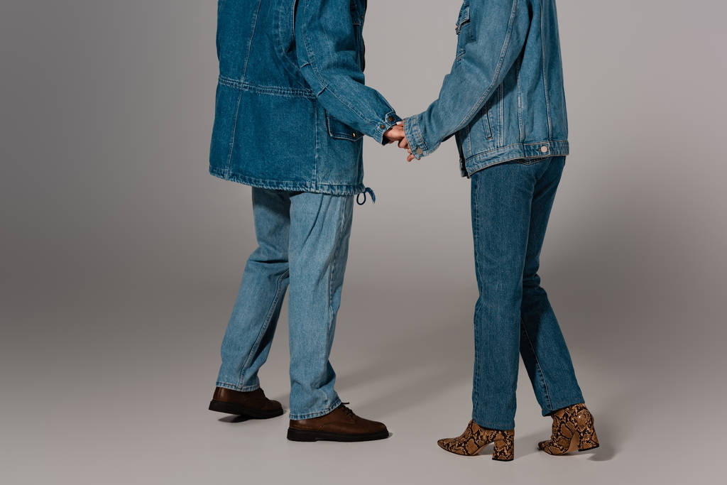 デニムジャケットのスタイリッシュな男性と女性のクロップドビューとグレーの背景に手を保持ジーンズ  - 写真・画像
