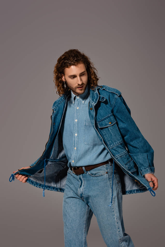 красивый и стильный мужчина в джинсовой куртке смотрит в сторону, изолированный от серого
 - Фото, изображение