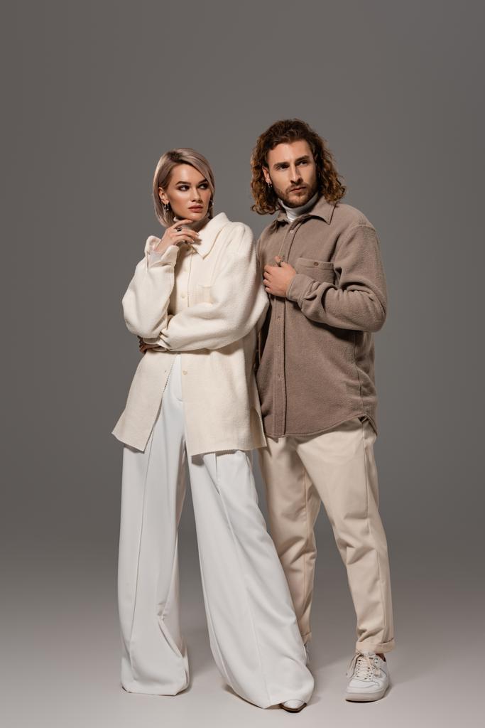 vrouw in witte jas en man in shirt weg te kijken op grijze achtergrond  - Foto, afbeelding