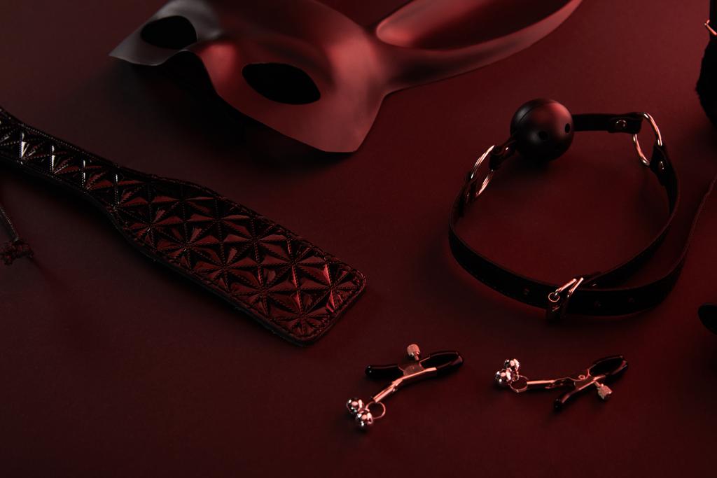 seksspeeltjes in donker licht op rode achtergrond - Foto, afbeelding