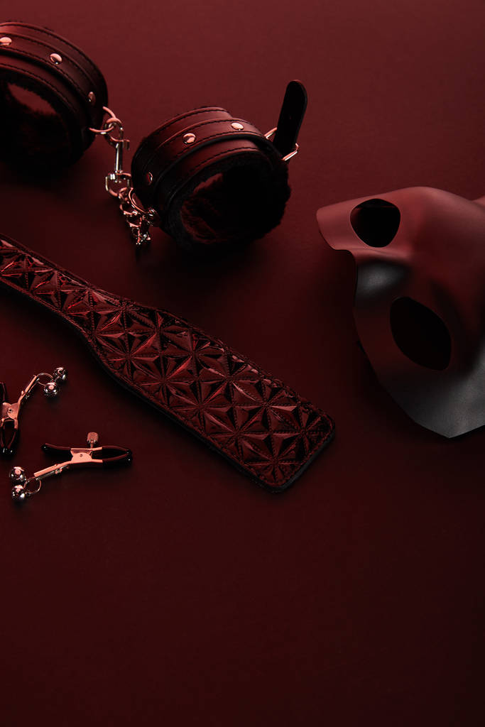 Sexspielzeug in dunkler Beleuchtung auf rotem Hintergrund - Foto, Bild