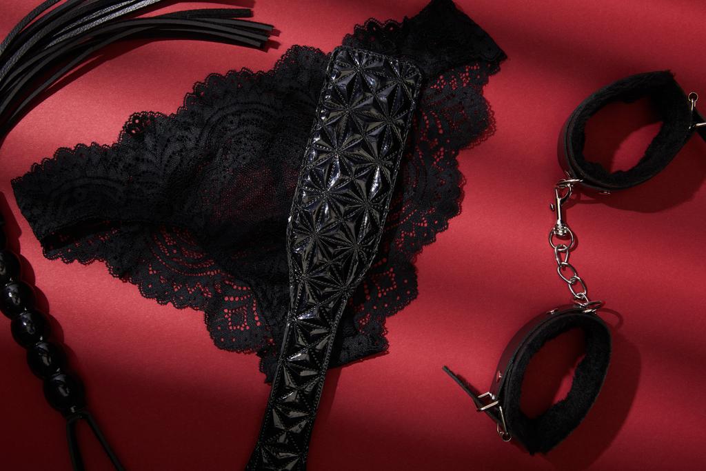 felső nézet fekete szex játékok és női bugyi piros háttér - Fotó, kép