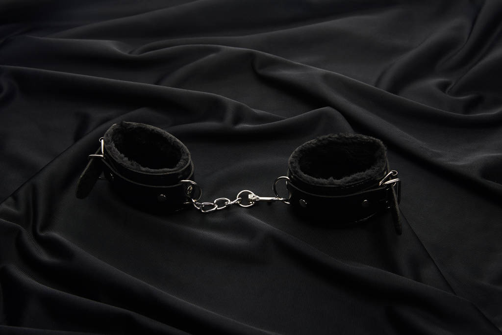 Lederhandschellen auf schwarzem Textilhintergrund - Foto, Bild