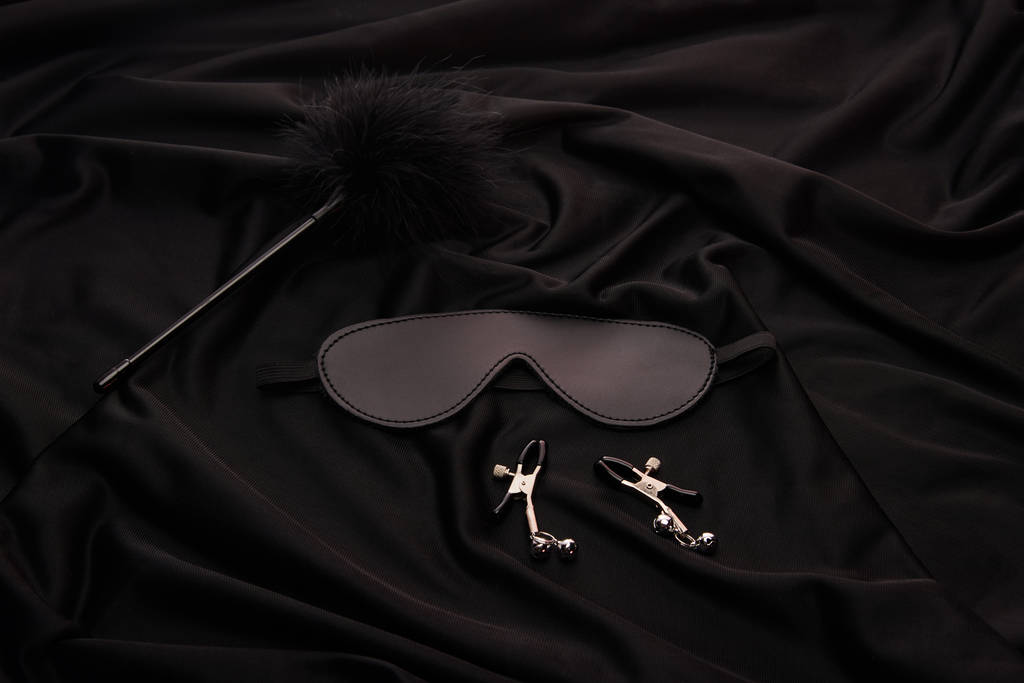 toll csiklandozó, maszk és mellbimbó szorítók fekete textil háttér - Fotó, kép