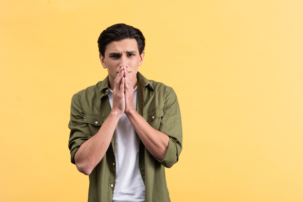 portrait of shocked young man holding hands together, isolated on yellow - Fotoğraf, Görsel