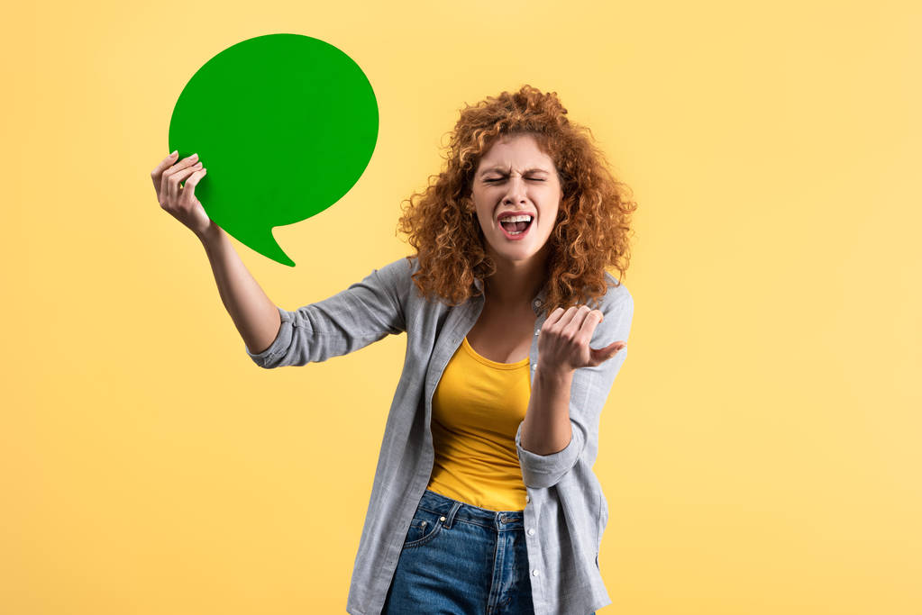 stressed woman holding empty green speech bubble, isolated on yellow   - Photo, Image
