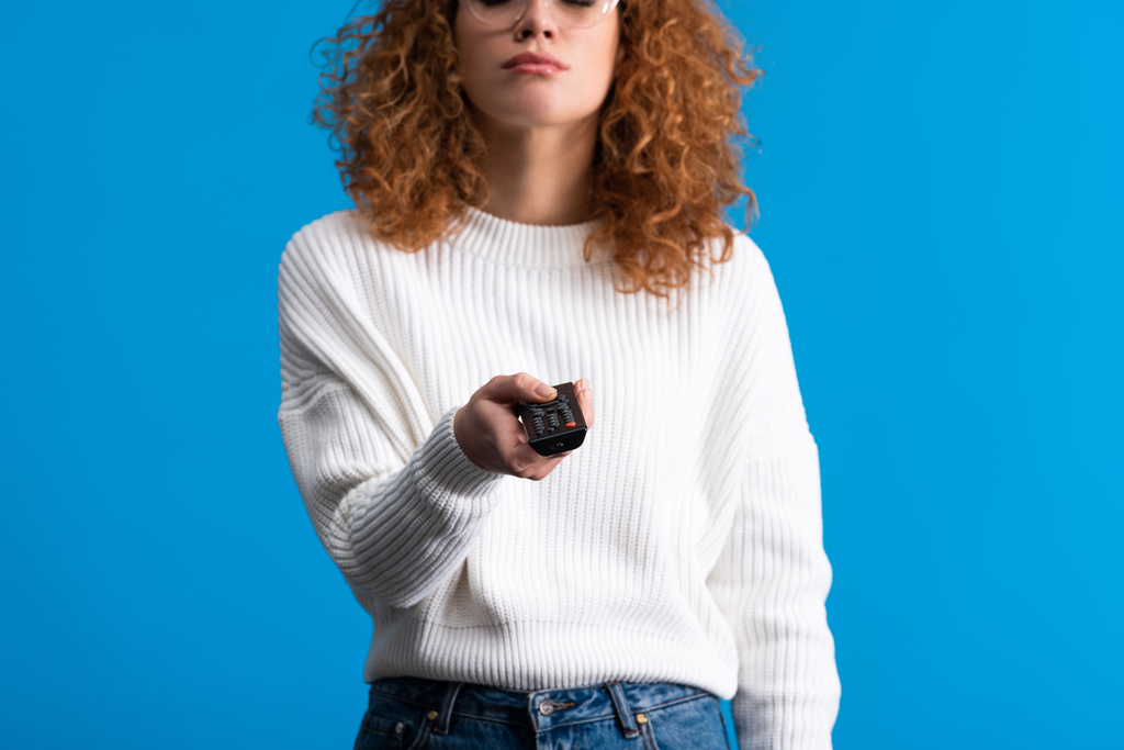 cropped view of girl holding remote control and watching tv, isolated on blue - Photo, Image