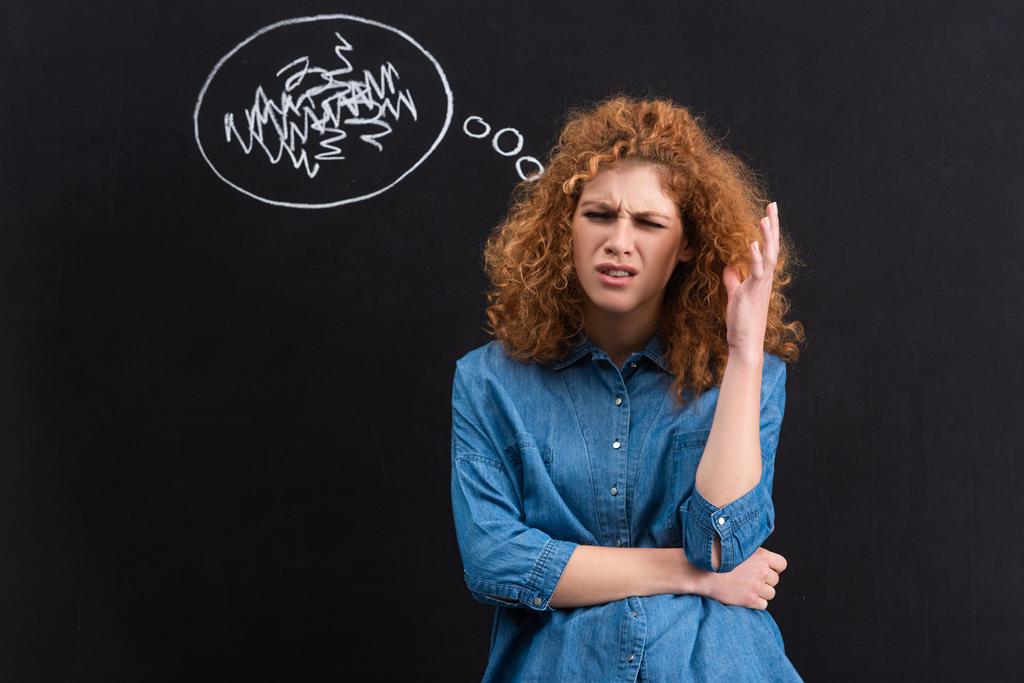 stressed redhead young woman with thought bubble on blackboard - 写真・画像