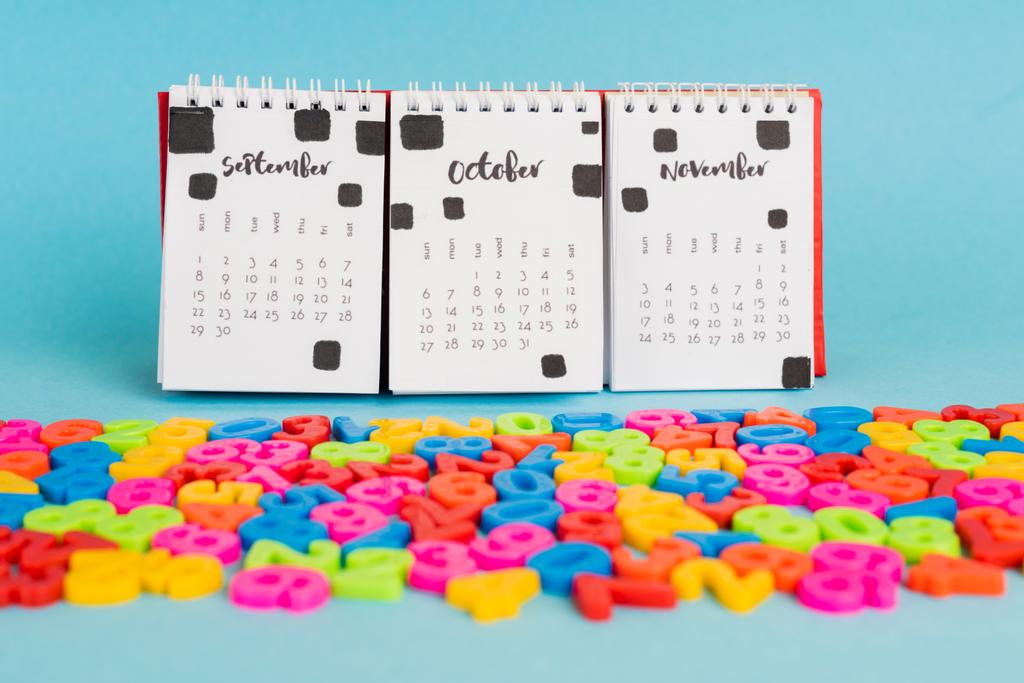 Kalender und bunte Plastikzahlen auf blauem Hintergrund - Foto, Bild