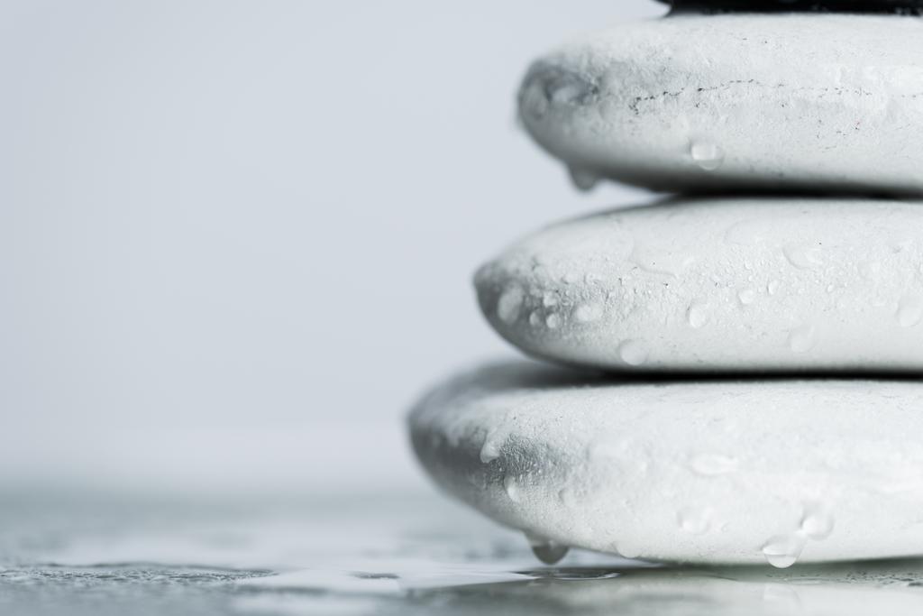 Макросъемка белых камней дзен в капли воды на влажном стекле, изолированные на сером
 - Фото, изображение