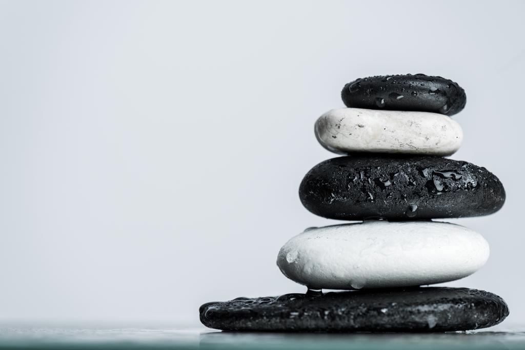 Close up view of water drops on stacked black and white zen stones on wet glass isolated on grey - Photo, Image