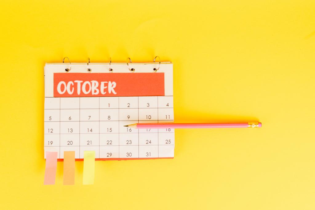 Draufsicht auf Bleistift auf Kalender mit November-Monat und Haftnotizen auf Daten auf gelbem Hintergrund - Foto, Bild