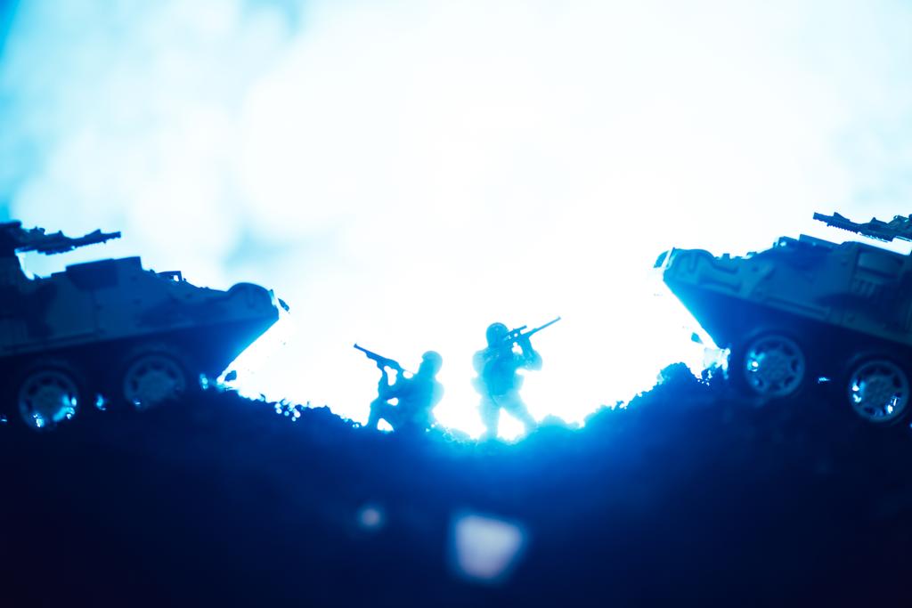 青を背景に煙とおもちゃの戦士や戦車の戦闘シーン - 写真・画像