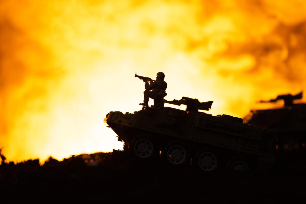 Silhouette eines Spielzeugsoldaten auf Panzer mit Feuer im Hintergrund, Kampfszene - Foto, Bild