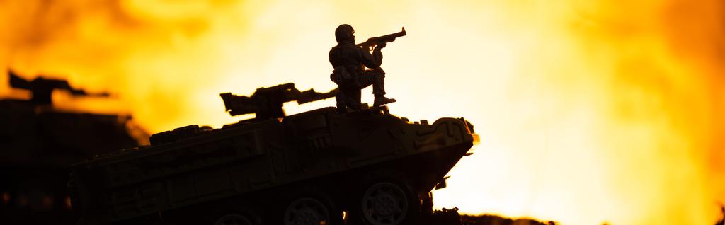 Scène de bataille avec silhouette de soldat jouet sur réservoir avec feu à l'arrière-plan, plan panoramique
 - Photo, image