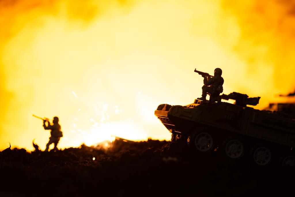 Soldados de brinquedo, tanques e explosão no campo de batalha com fogo no fundo
 - Foto, Imagem