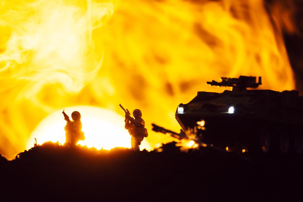 Escena de batalla con guerreros de juguete, tanque y humo con puesta de sol al fondo
 - Foto, Imagen
