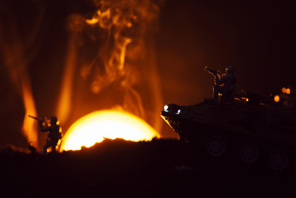 Сцена боя с игрушечными воинами и танком в дыму с закатом на заднем плане
 - Фото, изображение