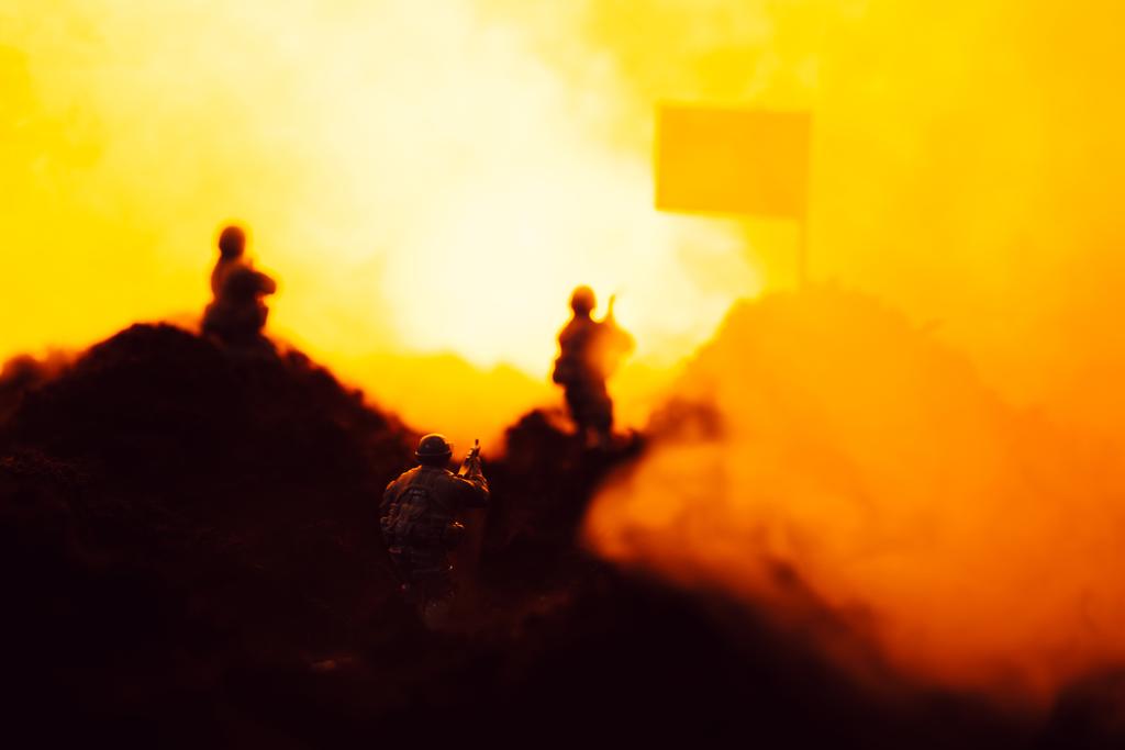 煙、旗、炎を背景に戦場でのおもちゃの戦士の選択的な焦点 - 写真・画像