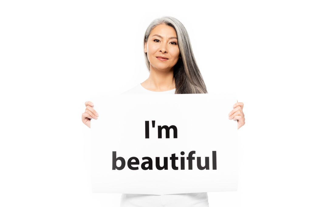 cheerful asian woman holding placard with i`m beautiful lettering isolated on white  - Photo, Image
