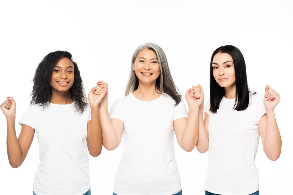 heureuses femmes multiculturelles regardant la caméra et tenant les mains isolées sur blanc
  - Photo, image