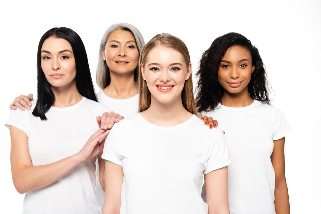 szczęśliwy wielokulturowe kobiety w białe t-shirty patrząc na aparat odizolowany na biały  - Zdjęcie, obraz