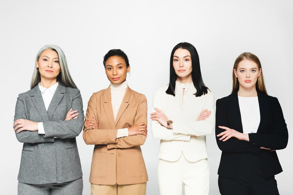 multiculturais mulheres de negócios em ternos de pé com braços cruzados isolados em branco
  - Foto, Imagem