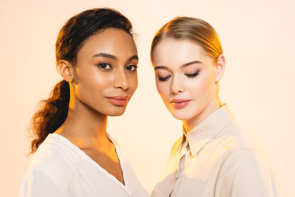 zwei attraktive multikulturelle Frauen mit Make-up isoliert auf beige  - Foto, Bild