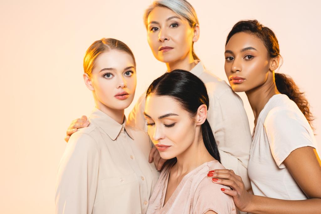 quatro mulheres multiculturais atraentes com maquiagem isolada em bege
  - Foto, Imagem