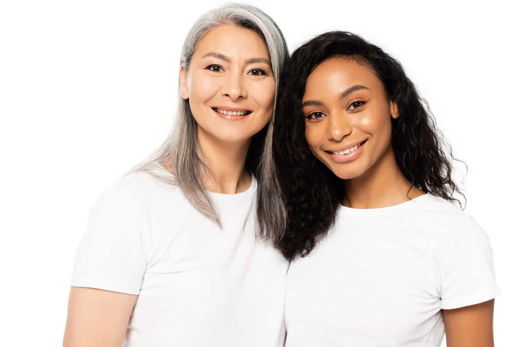 happy african american and asian women looking at camera and smiling isolated on white  - Photo, Image