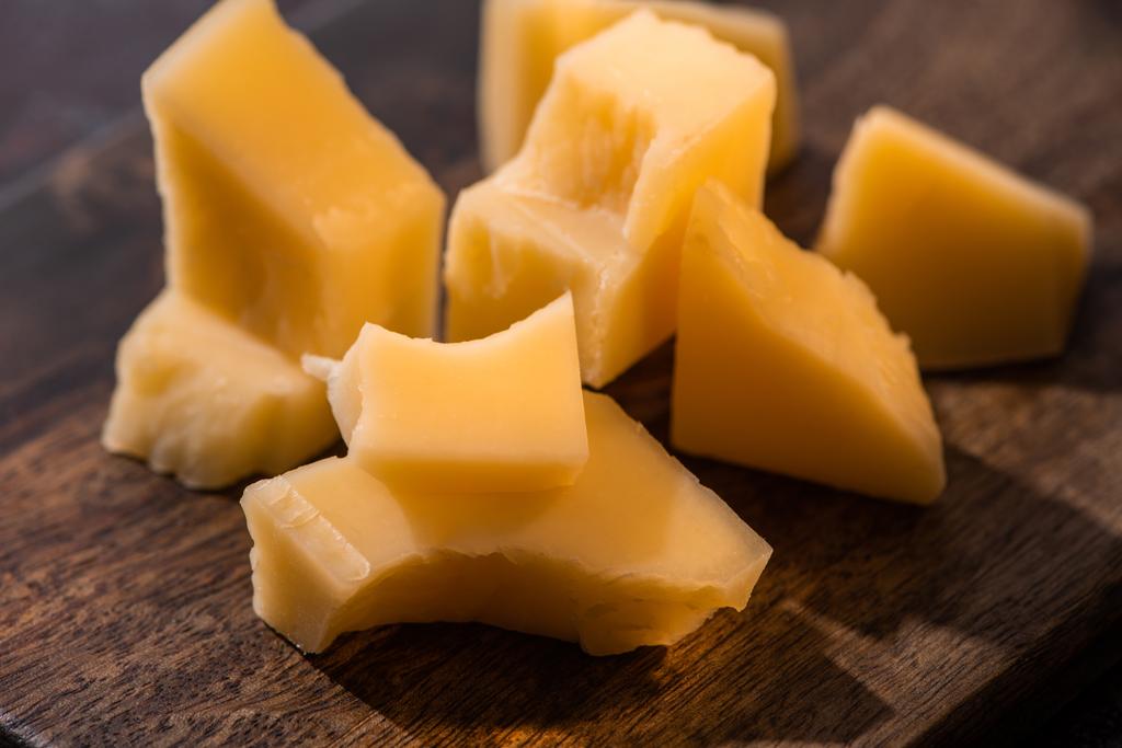 Güneş ışığında aşınmış yüzey üzerinde Grana Padano peyniri olan ahşap tabağı kapat. - Fotoğraf, Görsel