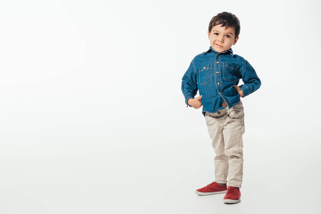 usmívající se chlapec v džínové košili při pohledu na kameru na bílém pozadí  - Fotografie, Obrázek