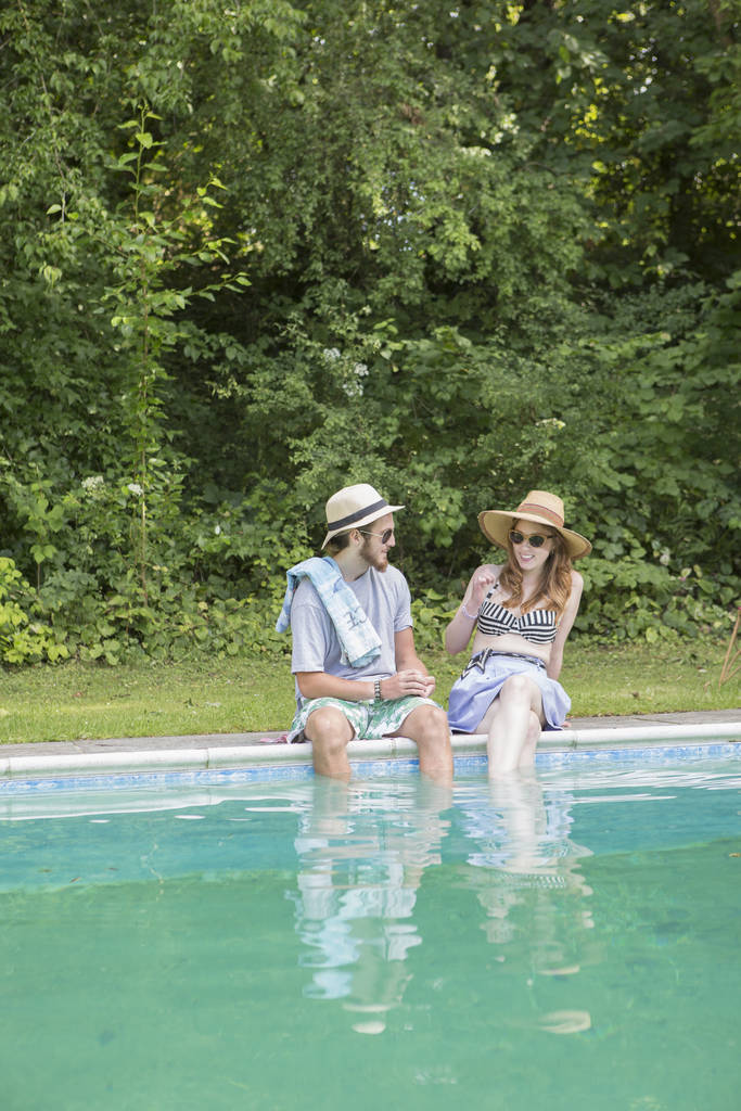 Couple dipping legs into pool - Photo, Image