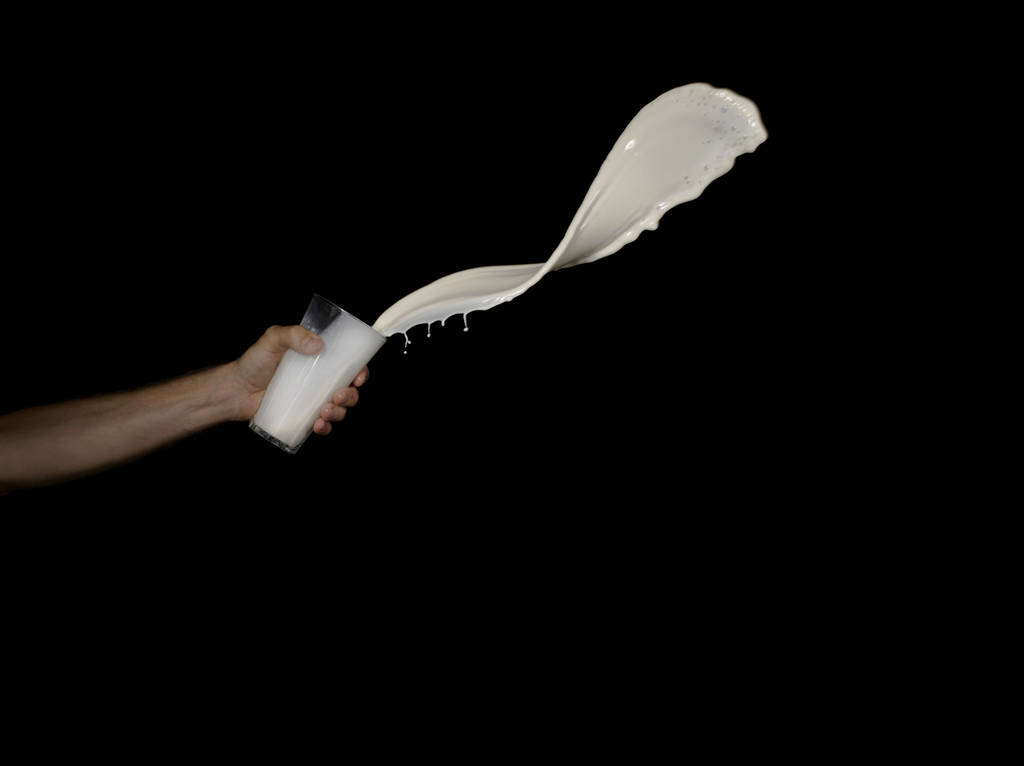 Ο άνθρωπος ρίχνει λευκό υγρό από ένα ποτήρι - Φωτογραφία, εικόνα