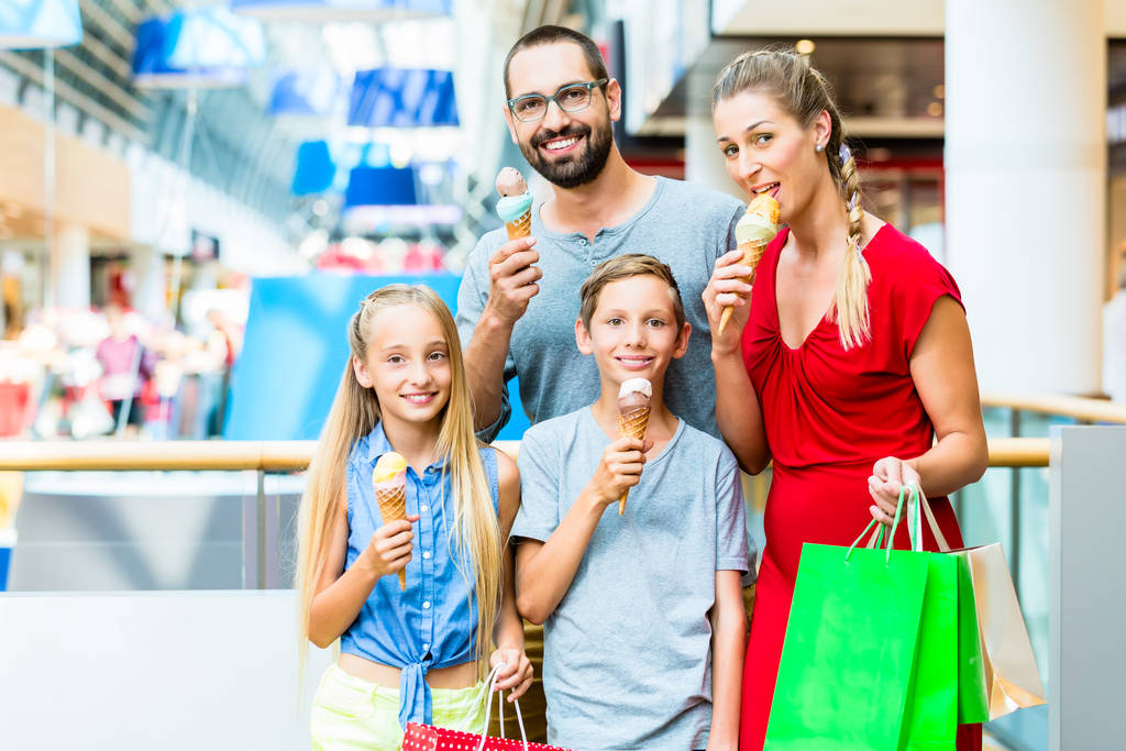 Сім'я їсть морозиво в торговому центрі з мішками
 - Фото, зображення
