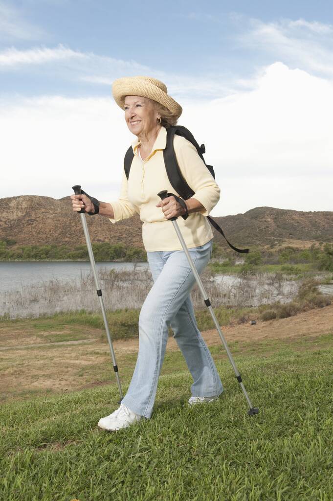 Plná délka šťastné starší ženy kráčející s turistickými tyčemi - Fotografie, Obrázek