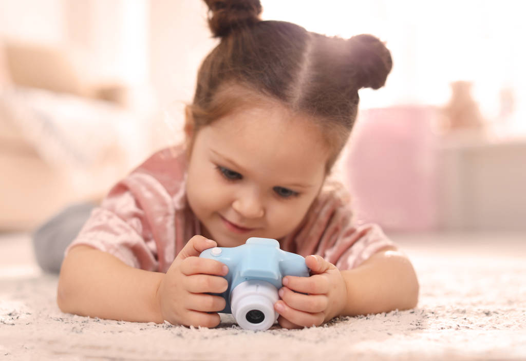 Piccolo fotografo con macchina fotografica giocattolo sul pavimento a casa
 - Foto, immagini